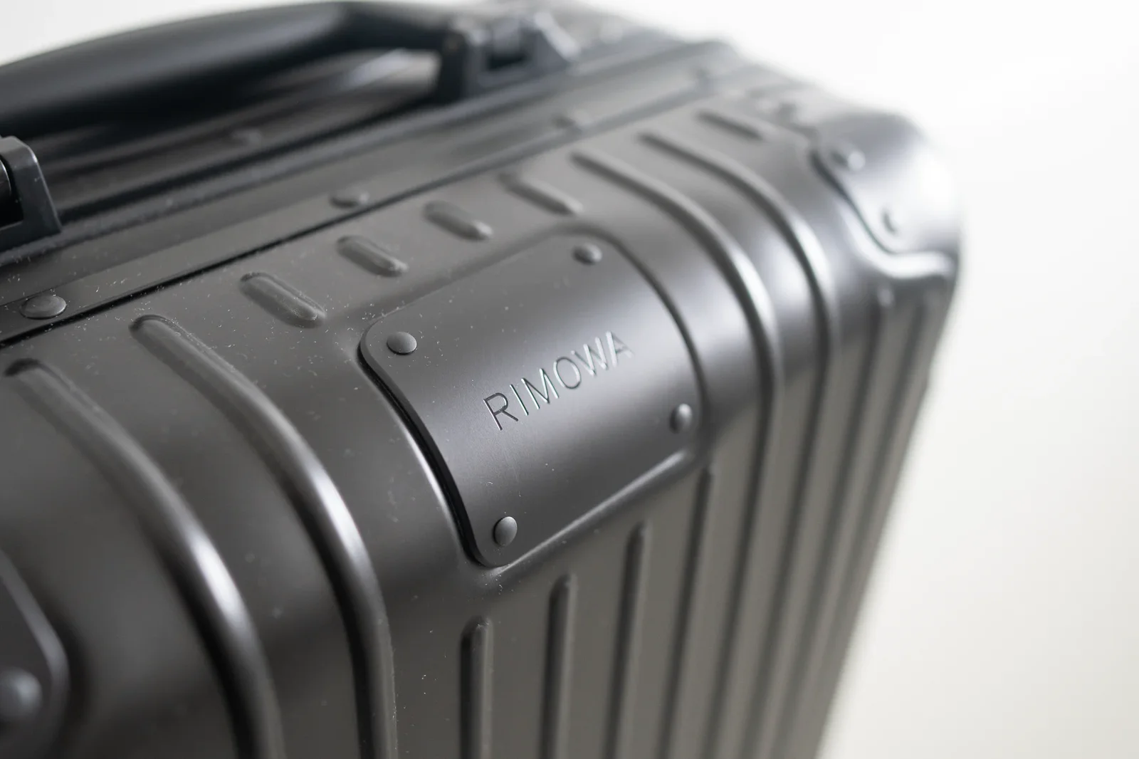 Black Rimowa Original Cabin aluminum carry-on, close-up of the grooved shell and logo plate